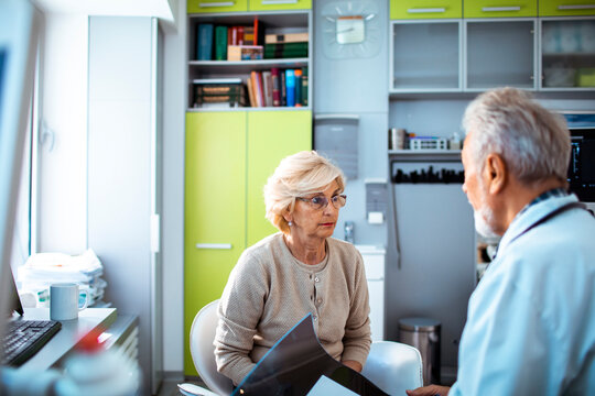 Senior woman discussing x-ray results with doctor in clinic
