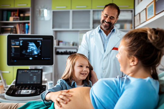 Pregnant mother with daughter and doctor during ultrasound in clinic