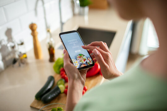 Person using recipe app on smartphone in home kitchen