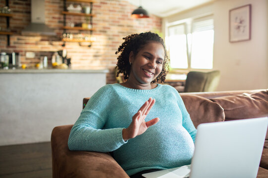 Smiling woman waving during video call at home