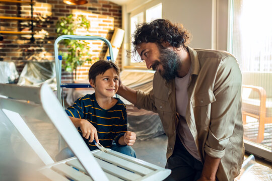 Father and son painting furniture at home