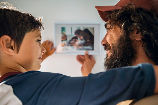Father and son hanging framed family photo at home
