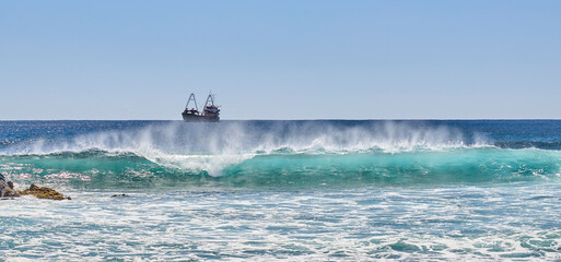 Brechende Wellen an der Küste der Galapagos-Inseln mit Schiff am Horizont © Olgierd Kajak