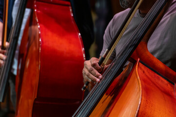 Musician's hand holding a bow and playing a string instrument, symbolizing artistic expression, dedication to craft, and the beauty of live orchestral music - stock photo © Amaiquez
