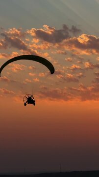 Paramotor flying over desert dunes at sunset in Qatar, powered paragliding adventure