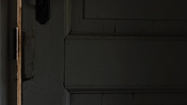 Male hand reaching, gripping and pulling painted door edge, sealing gap to darken room for interior