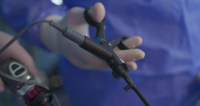 Close-up of a surgeon&rsquo;s gloved hand holding a laparoscopic grasper instrument during a minimally invasive surgical procedure.