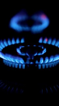 Vertical view of blue double flame of a gas stove with red highlights and with focus change on a black background in slow motion and copy space for text