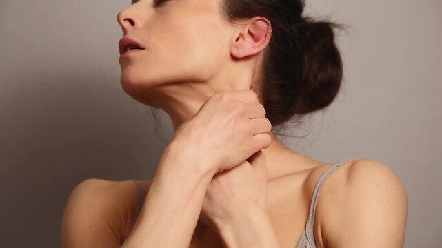 Beautiful woman doing stretching and massaging exercise the neck platysma muscle for healthy face skin, beauty and youth, freshness in studio lighting. Closeup healthy lifestyle video	
