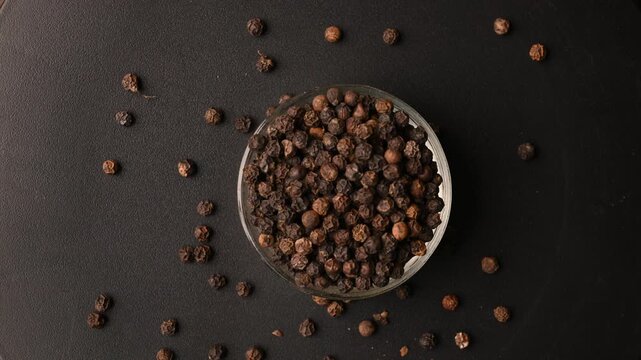Top View of Black Pepper Seeds (Kali Mirchi) in Bowl on Black Background &ndash; Rotating Footage