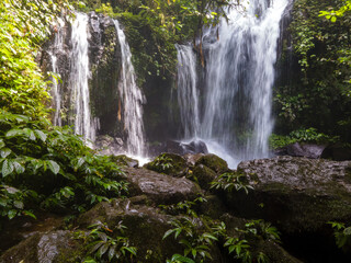 Obraz premium Aerial View of Rambat Waterfall in Tropical Forest, Nature Scenery from Above. Hidden Jungle Waterfall Rambat, Aerial Nature View Indonesia
