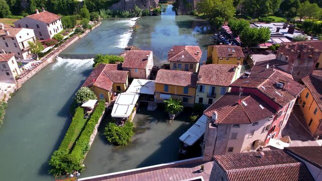 Italy Borghetto sul Mincio Aerial 4K Video Drone Flight Over River and Cascading Waterfalls Between Medieval Colorful Houses Unique Village Near Lake Garda Scenic Travel and Hidden gems