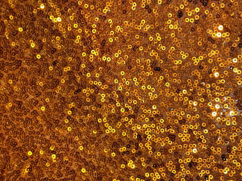 Close up of gold fabric with bokeh and sparkling effect. Luxurious yellow gold background with glittering golden sequins. Seamless background texture