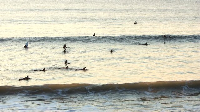 Surfers waiting and catching waves in the surf mecca of Croyde in Devon at sunset, one of the best surf breaks in Europe