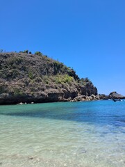 Naklejka premium clear turquoise water near a rocky cliff under a bright blue sky