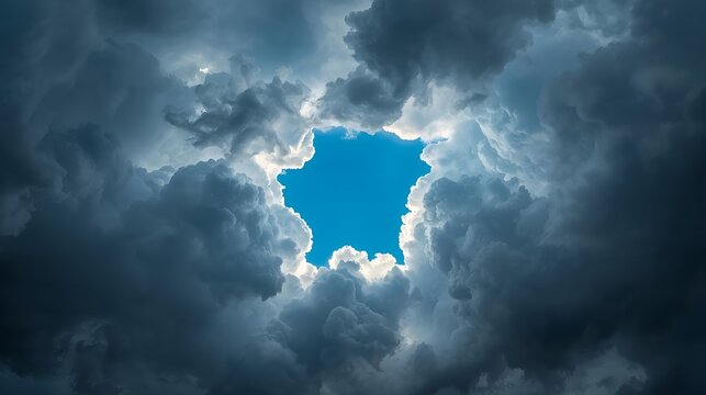Dramatic blue sky opening in storm clouds with sunlight rays and hope concept