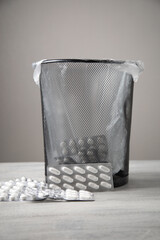 Medical pills and trash bin on the table.