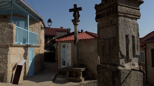 Sunny village square with stone cross and traditional architecture