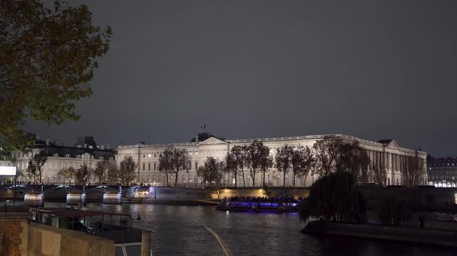 Louvre Museum at night with tourist boat on Seine River
