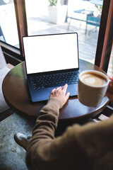 Vertical mockup image of a woman working on laptop computer with blank white desktop screen while drinking coffee in cafe
