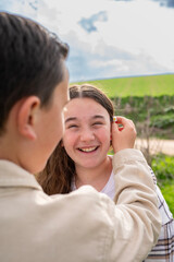 Fototapeta premium Boy placing daisy behind smiling girl’s ear outdoors