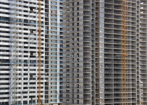 Construction cranes and unfinished building as background backdrop. Industry concept.  incomplete brick building. It is the unfinished European apartment building. Batumi Georgia Orbi