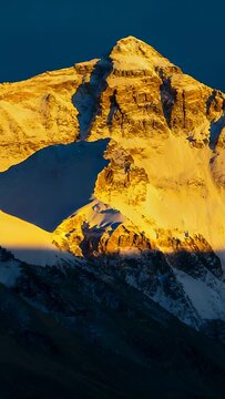 Vertical video: Bathing snowy peak on alpine ridge, sunlight shifting downward showing cornices