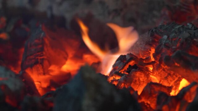Burning charcoal surface with bright embers and dark texture creating a powerful abstract fire background.