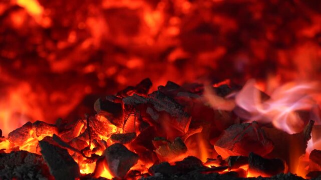 Burning charcoal surface with bright embers and dark texture creating a powerful abstract fire background.