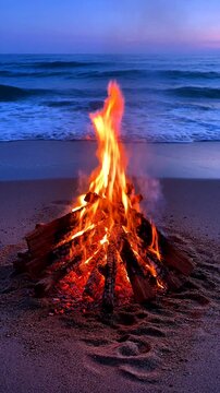 A vibrant campfire burns on the beach as waves gently lap at the shore during a serene sunset.