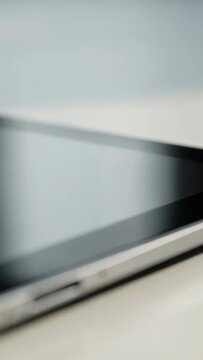 Vertical video: Shifting camera focusing on tablet on white tabletop, showing bezel and USB-C port