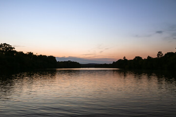 Fototapeta premium Calm lake at sunset with soft sky and water reflection background