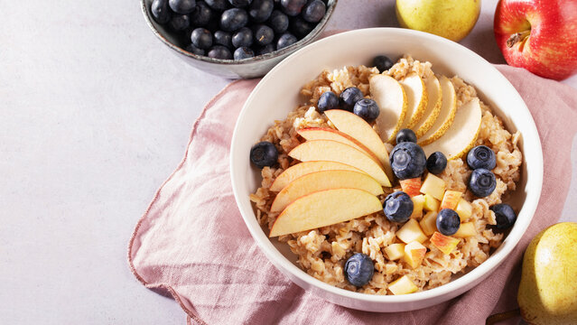 Bowl of oatmeal with apple, pear and blueberries, diabetes friendly and blood pressure friendly whole grain breakfast scene, healthy cardiometabolic lifestyle concept