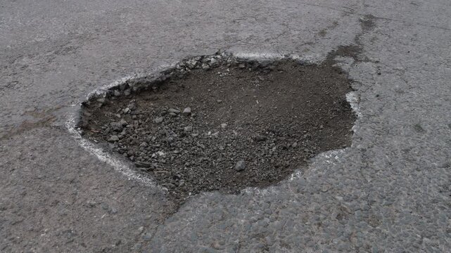 Damaged asphalt road with a large pothole