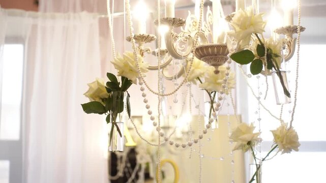 Elegant white floral arrangement with greenery in decorated hall, blurred string lights behind, with copy space. Concept for wedding, invitation background, celebration, romantic event