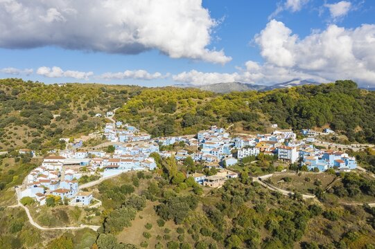 The village of J&uacute;zcar above the Genal river valley, the houses of this former White Village have been painted in smurf-blue to celebrate the premiere of the Smurfs movie, aerial view, drone shot, Serran&iacute;a de Ronda, M&aacute;laga province, Andalusia, Spain