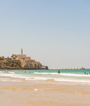 Surfers on the beach, Alma Beach, behind the old town of Jaffa with St. Peter's Church, old port, Tel Aviv-Jaffa, Israel