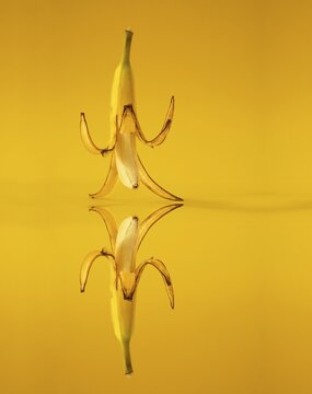Banana with peel against a yellow background