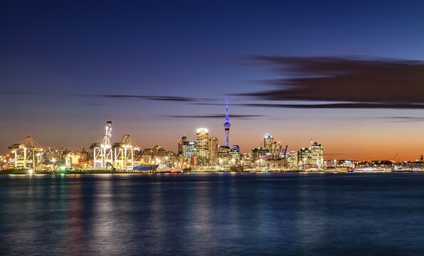 Illuminated skyline of Auckland at sunset, Waitemata Harbour, Sky Tower, Central Business District, Auckland, North Island, New Zealand