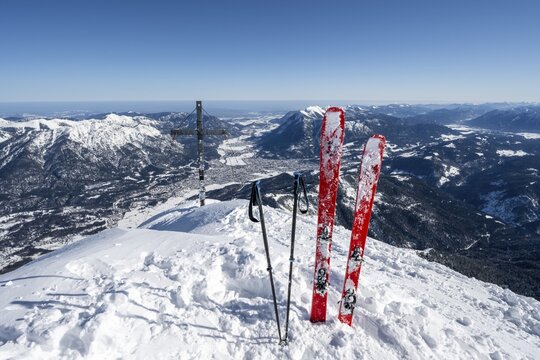 Ski stuck in snow, Alpspitz summit with summit cross, ski tour to Alpspitze, view to Garmisch-Patenkirchen, Wetterstein mountains with snow in winter, Garmisch-Partenkirchen, Bavaria, Germany