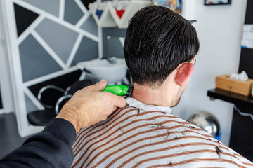 Obraz premium Precision fading at the nape using electric clippers, ideal for concepts of hygiene, craftsmanship, and routine personal maintenance.