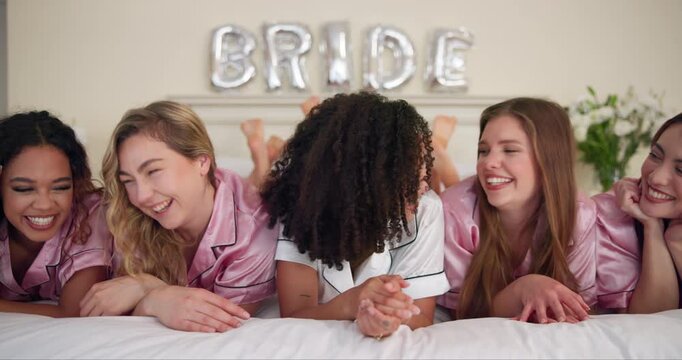 Women, people and laughing in bed for bridal shower, celebration and bonding in hotel bedroom. Group, happy friends and joke with bride for support, solidarity and sisterhood in bachelorette party