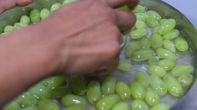 Fresh green grapes being washed in a bowl of water