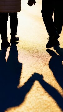 Pair walking holding hands, first step causing shadow shift on sunlit pavement bonding for branding