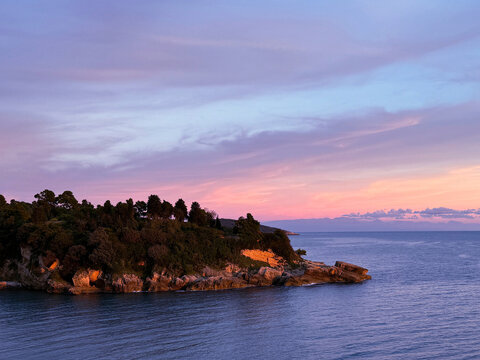 Sunset sky over calm sea and rocky coastline at evening.