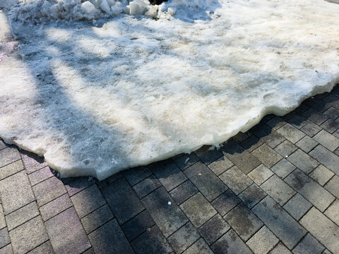 Melting snow on sidewalk in early spring city