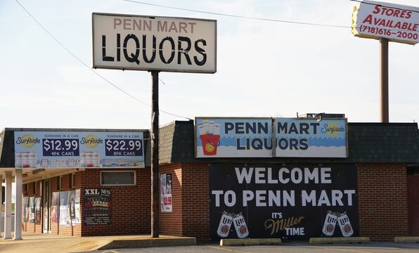 New Castle, Delaware, U.S - March 22, 2026 - Penn Mart Liquor store exterior featuring multiple product advertisements, pricing signs, and branding for beverages including Surfside and Miller Lite.
