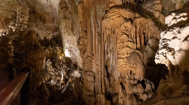 Limestone cave interior with stalactites and stalagmites illuminated in underground chamber