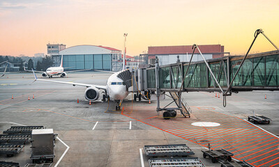 An airliner is parked at a terminal gate connected to a boarding bridge on an airport tarmac during...