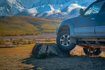 Close up of off-road 4x4 vehicle wheel climbing a large rock in mountain valley. Suspension articulation, expedition and extreme adventure travel concept. © ANDREY